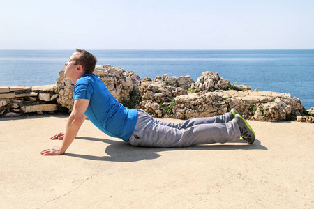 运动的人做伸展运动, 准备在海边锻炼。英俊的健身运动员做伸展运动, 练习瑜伽, 冥想, 普拉提在阳光下。背景中的天空和海洋