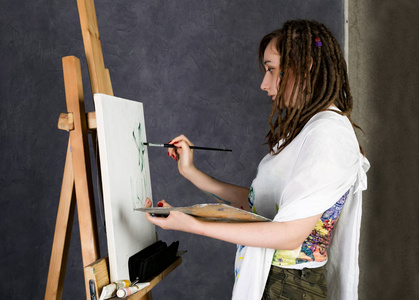 女性绘画艺术家提出下一步的画架和颜料在画布上，描绘了遐想