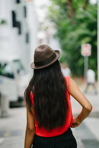 一个年轻的印度亚洲模特的肖像, 戴着一顶顶着帽子站在亚洲的小巷里。她优雅漂亮高大。