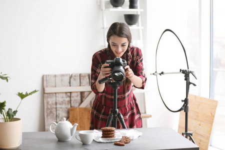摄影棚的年轻妇女与专业照相机拍摄食物照片