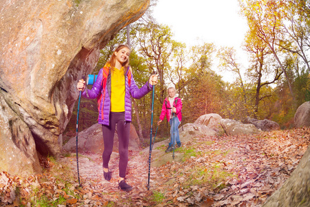 快乐的游客年轻的女孩与徒步手杖在秋季探索山区小径