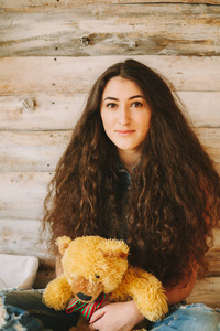 一个玩具熊，在一个木制的背景上的时髦女孩