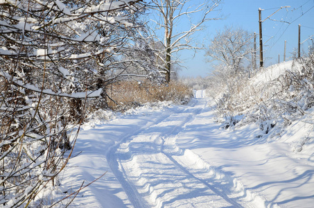 一条平行于铁路线的路在大雪后的晴天被雪覆盖着。
