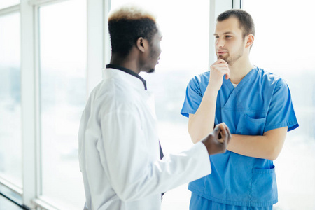 博士会议。混合种族两位自信的医生站在医院, 讨论病人