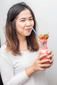 有趣的亚洲妇女喝草莓奶昔自制的白色背景