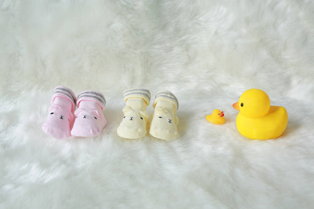 婴儿袜子在白色毛皮背景与装饰橡胶鸭子