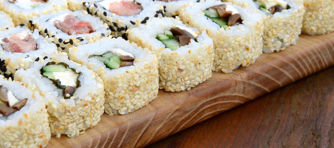 许多寿司卷的特写是用不同的馅料躺在木质表面上的。烹饪经典日本美食的宏拍与复制空间