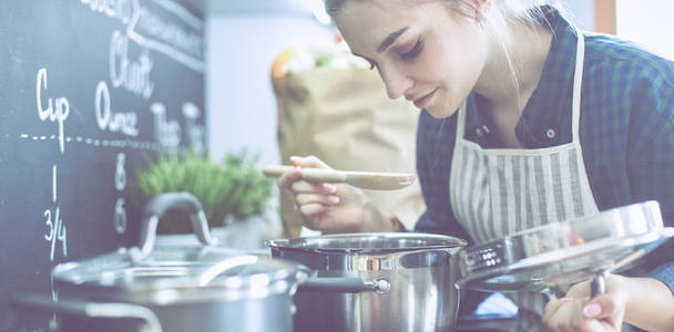 她厨房站附近炉子做饭的年轻女人