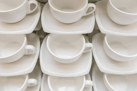 许多排干净的白咖啡杯, 茶勺和碟子在桌子上。一排空杯准备咖啡歇