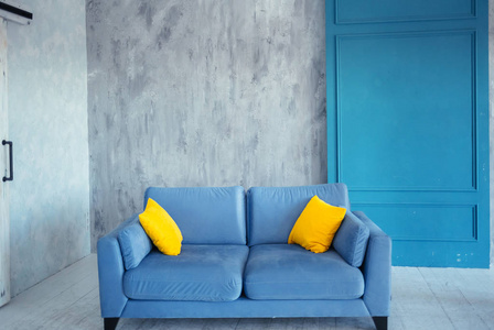 蓝色现代沙发和两个黄色枕头在舒适的公寓