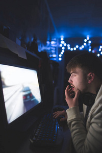 一个留胡子的年轻人晚上在家玩电脑游戏。