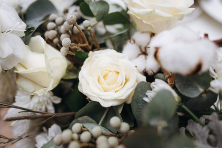 花的组成与白色玫瑰, 白色的花朵, 芽, 绿叶和装饰植物的背景模糊