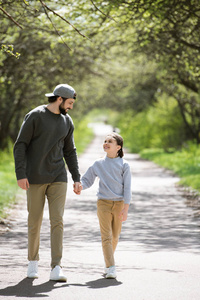 微笑的父亲和女儿在公园散步和牵手