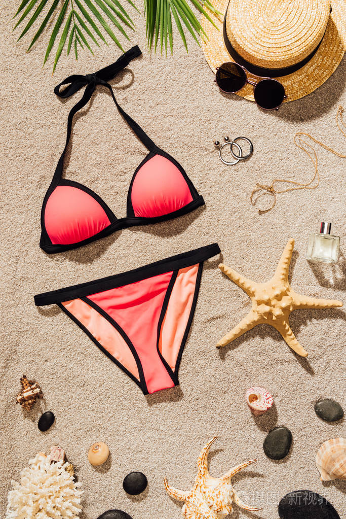 在沙滩上的各种配件的时尚粉红色比基尼的顶级视图