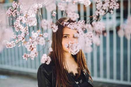 年轻美丽的女孩站在粉红色的春天粉红色的树下