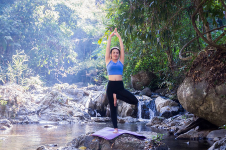 妇女沉思在河岩石做瑜伽