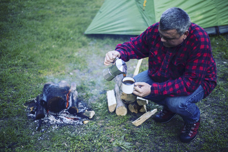 一个男人正在营地的篝火上准备早餐。
