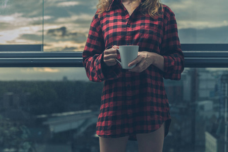 日出时在阳台上喝咖啡的妇女