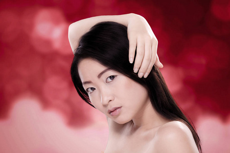 美丽的中国妇女与健康头发对模糊的红色背景