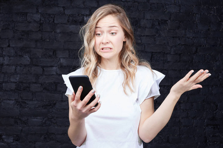 愤怒的女人在智能手机上读短信提醒她有关账单, 需要立即还债, 皱眉