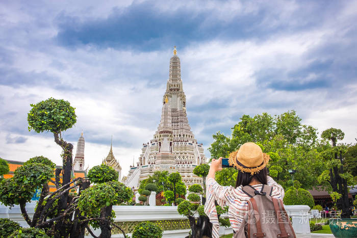 带背包的亚洲女性游客在旅途中带着智能手机拍照或自拍, 在塔阿伦庙度假时放松一下, 这是泰国曼谷的地标和景点。