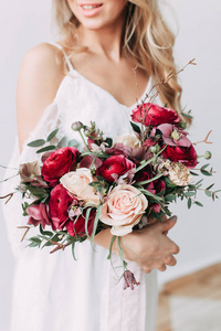 新娘穿着浅色婚纱, 带着一束红花, 在斯堪的纳维亚风格的一盏轻型墙上。欧洲婚礼现代趋势与启示