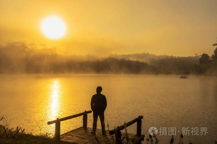 剪影消沉人站立在船上湖在日出时间戏剧性和孤独概念