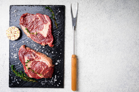 生肉。在一个切板上的生牛排与迷迭香和香料, 顶部视图