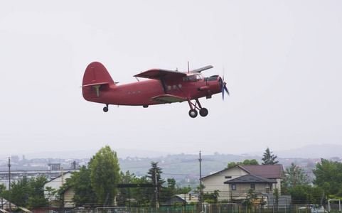 老式红色飞机飞越城市上空