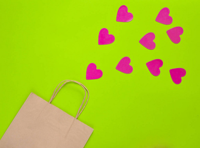 爱购物的概念。一个纸袋购物和许多装饰心在一个绿色的背景。情人节。顶部视图