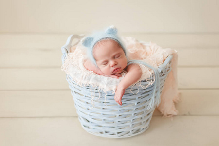 新生儿睡在一个柳条篮在一个蓝色蓬松针织猫