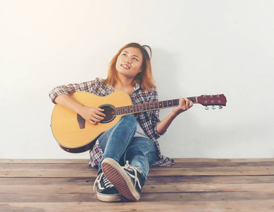 时髦的女人风格的肖像与吉他的样子很高兴