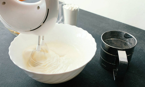 特写女人手用搅拌机在碗里把鸡蛋和糖搅在一起。烹饪苹果派