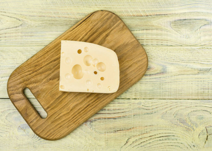 一块有大孔的奶酪在木制的切板上