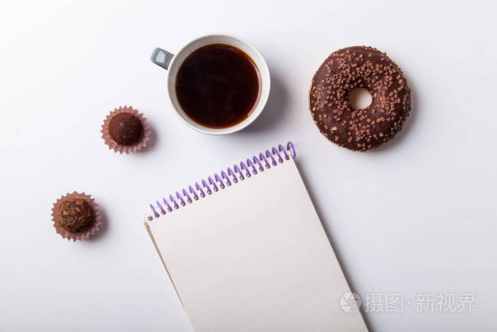 巧克力甜甜圈与松露和杯黑色的咖啡与空白笔记本隔离在白色背景, 特写