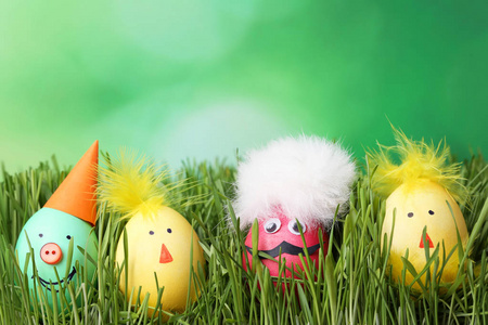 绿草中有滑稽面孔的鸡蛋