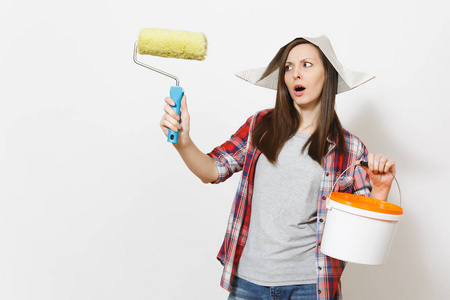报纸的帽子有关妇女在报纸帽子持有油漆辊为墙壁绘画和空的油漆桶与