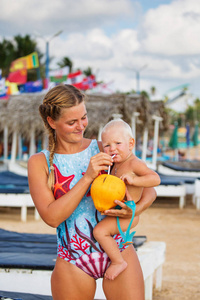 一位母亲和儿子在沙滩上喝椰子