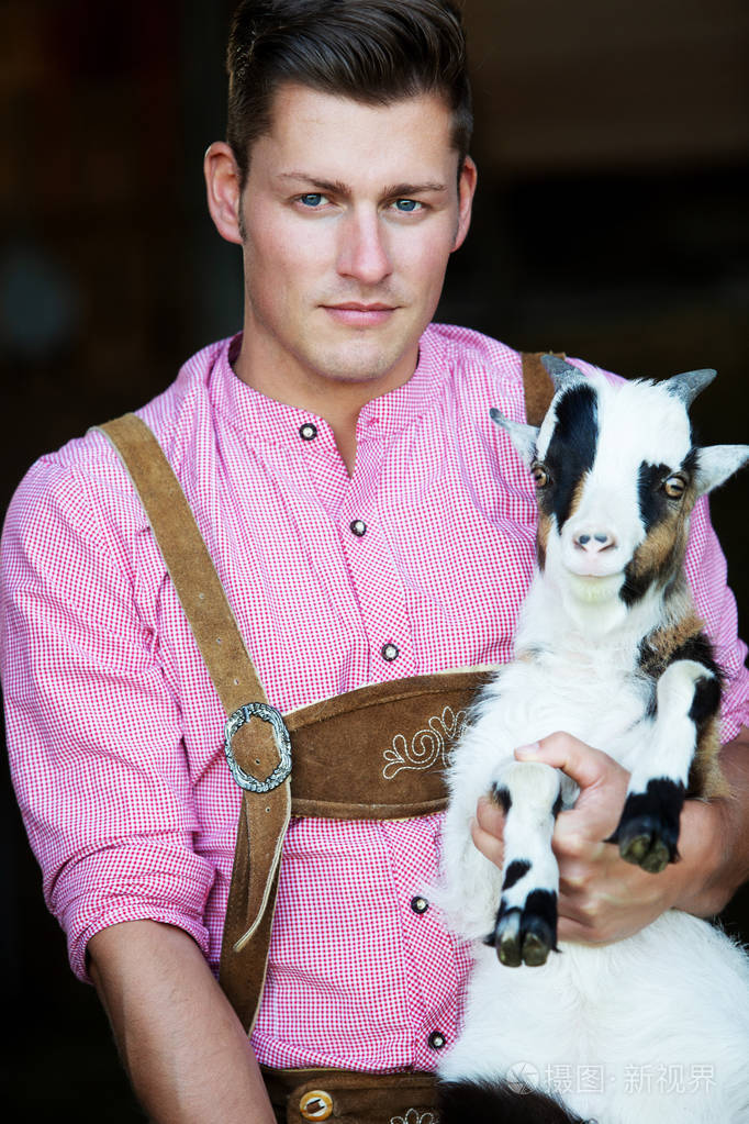年轻的巴伐利亚人抱着一只山羊