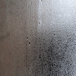 质地的一滴雨在玻璃湿透明的背景上。灰色色调