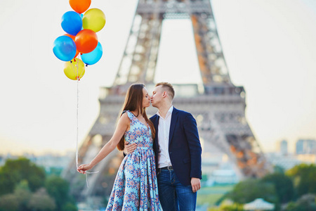 恩爱夫妻束五颜六色的气球,在法国巴黎的埃菲尔铁塔附近接吻照片