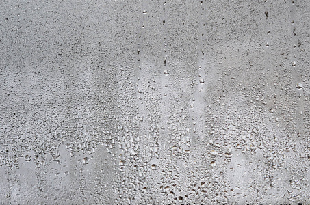 质地的一滴雨在玻璃湿透明的背景上。灰色色调