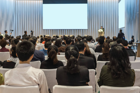 在会议大厅或研讨会上的观众后视图, 其中有关于投资概念的舞台商业和教育的演讲者