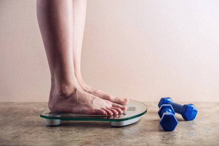 女性脚站立在电子秤为重量控制在轻的背景。运动训练的概念, 饮食