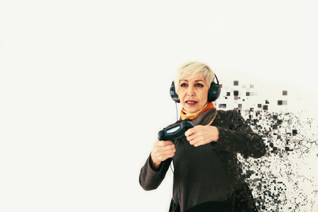 一位年长的妇女玩视频游戏, 被分割成像素。具有视觉效果的概念性照片, 意味着老年人和新技术