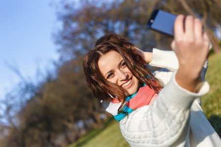 在公园户外拍摄时尚时髦微笑女生，手机使自拍照