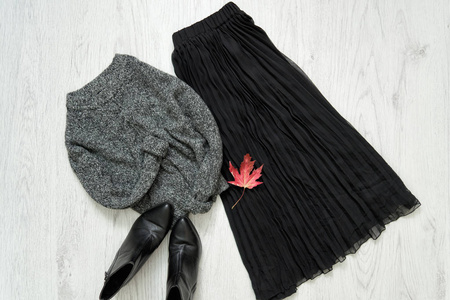 灰色暖和的毛衣, 黑色的裙子和靴子。时尚理念
