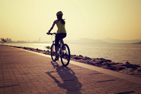 海边晨练骑车骑山地自行车的女人在海边照片