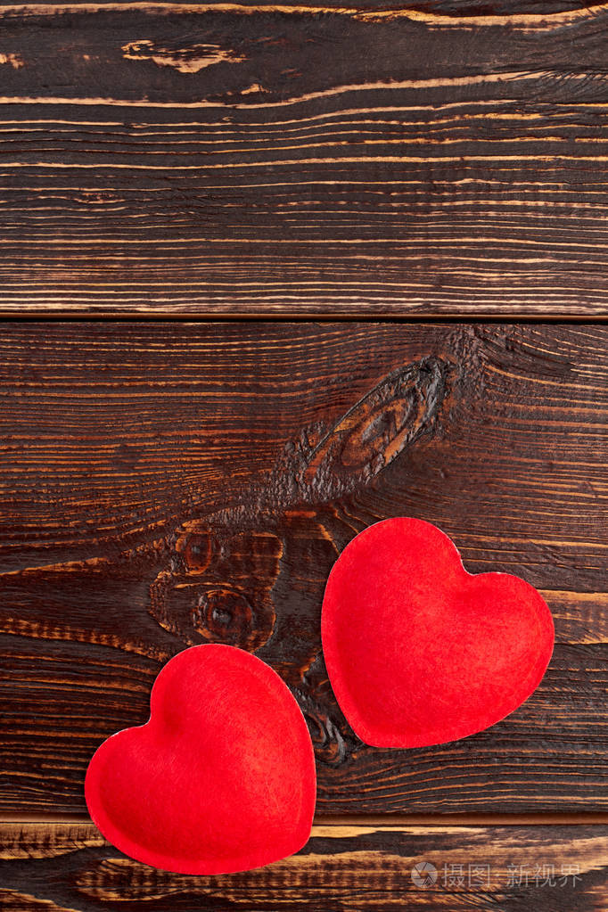 两颗红色的心在木质背景上