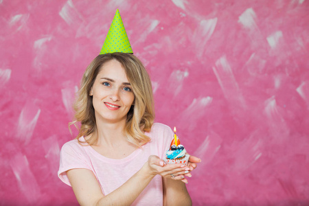 漂亮金发女孩生日帽在举行着蜡烛的蛋糕